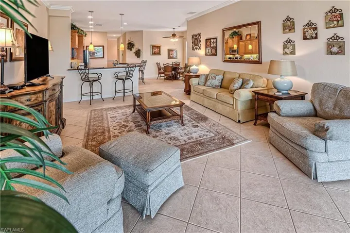 Living room with light tile patterned floors, a ceiling fan, and crown molding