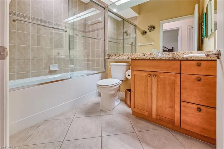 Full bathroom with bath / shower combo with glass door, vanity, and light tile patterned floors