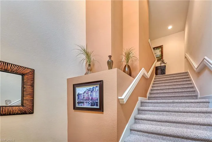 Stairway featuring a textured wall and recessed lighting