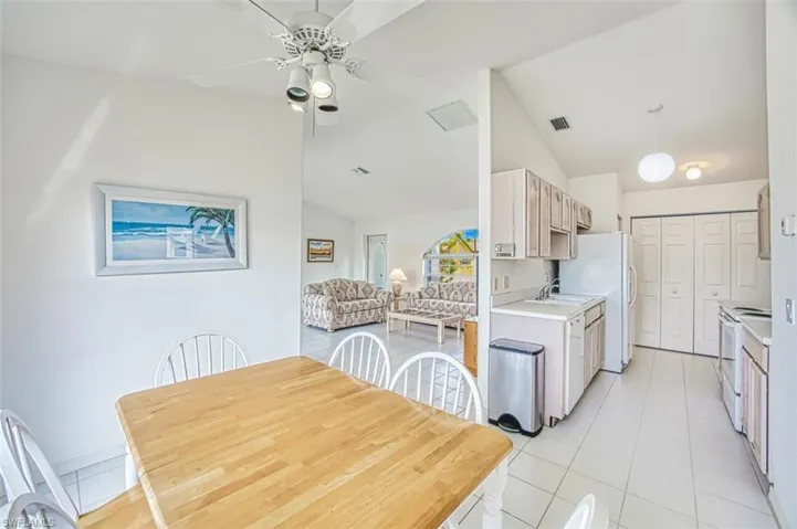 Dining area featuring ceiling fan, visible vents, vaulted ceiling, and light tile patterned floors