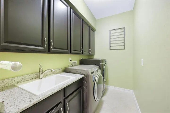 Large laundry area featuring cabinets, sink, tile flooring, dryer & new washer