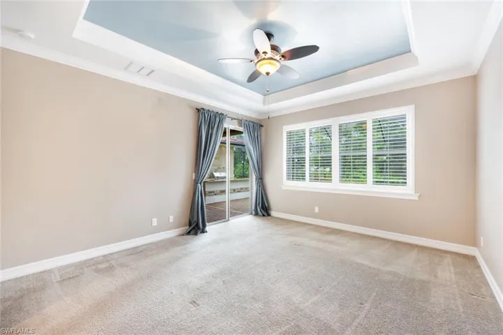 Master bedroom with tray ceiling & plantation shutters with pool view