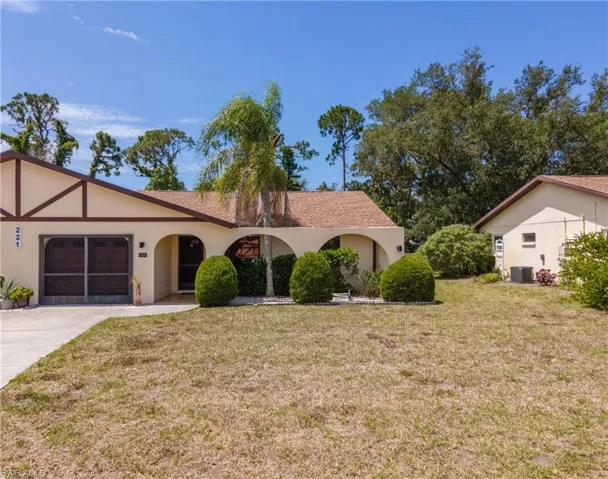 Front exterior featuring arched entryway, stucco facade, and an attached garage with a screened door