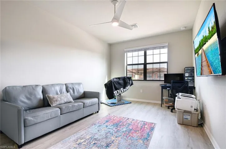 Living room with an office area, light wood finished floors, and a ceiling fan