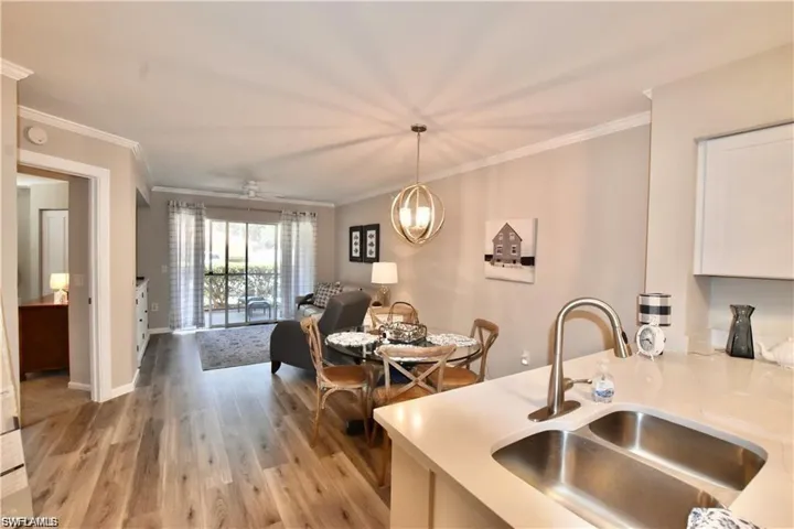 Kitchen with light wood finished floors, open floor plan, ornamental molding, decorative light fixtures, and a chandelier
