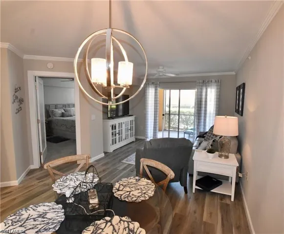 Dining room featuring crown molding, a chandelier, dark wood-type flooring, and ceiling fan