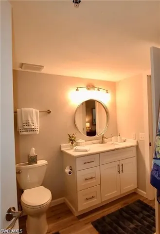 Half bath with wood finished floors and vanity