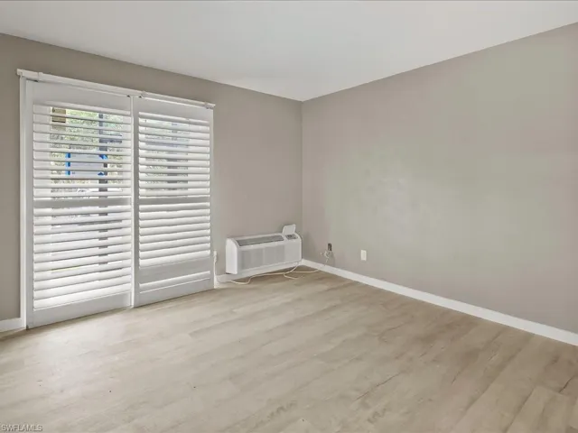 Unfurnished room featuring light wood finished floors and an AC wall unit