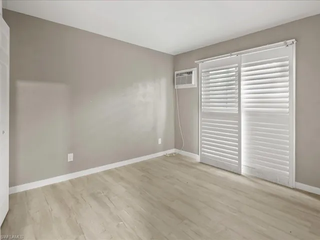 Unfurnished bedroom featuring light wood finished floors and a wall mounted air conditioner