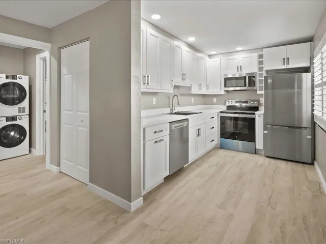 Kitchen with stainless steel appliances, white cabinetry, light wood finished floors, and recessed lighting