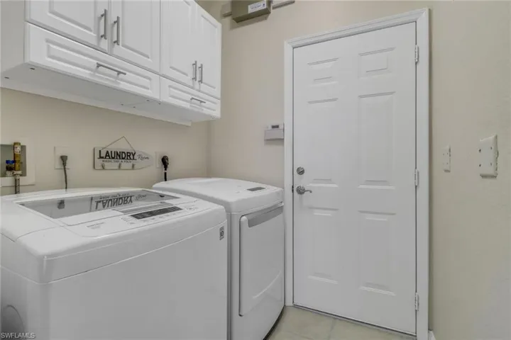 Laundry area with independent washer and dryer, cabinet space, and light tile patterned floors