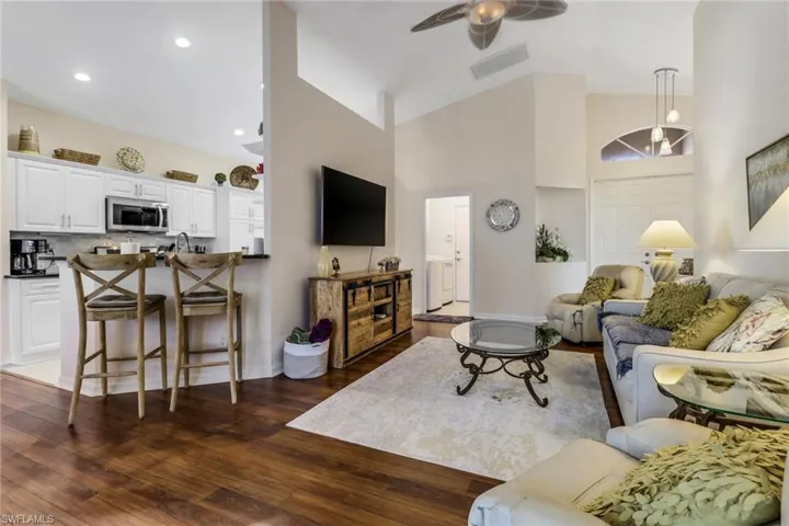 Living area featuring high vaulted ceiling, dark wood-style floors, and ceiling fan