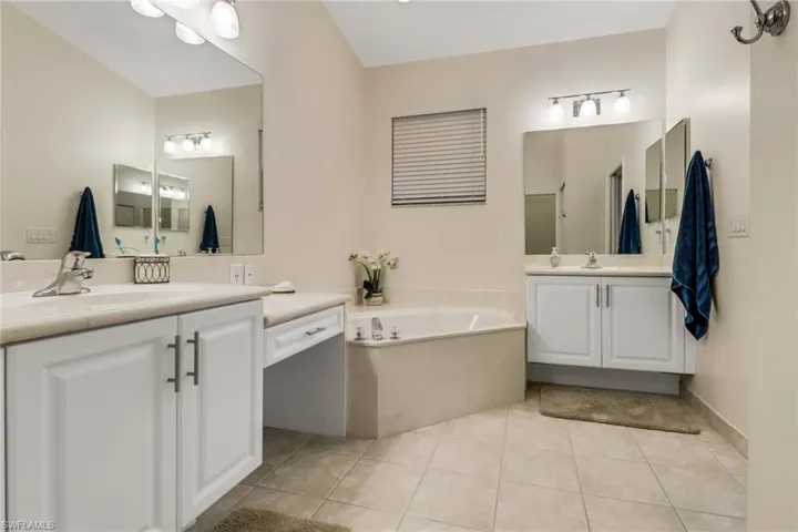 Full bath with two vanities, tile patterned floors, and a bath