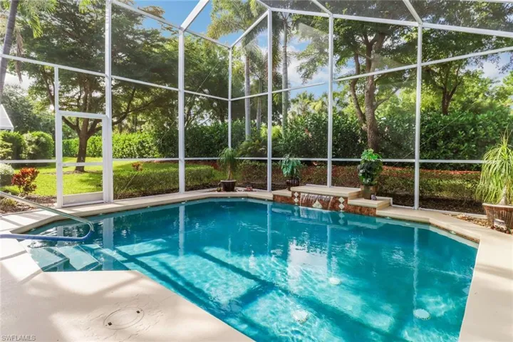 Swimming pool with a lanai and view of wooded area