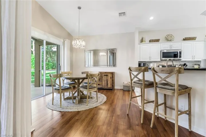 Dining space featuring dark wood-style flooring, lofted ceiling, a chandelier, and recessed lighting