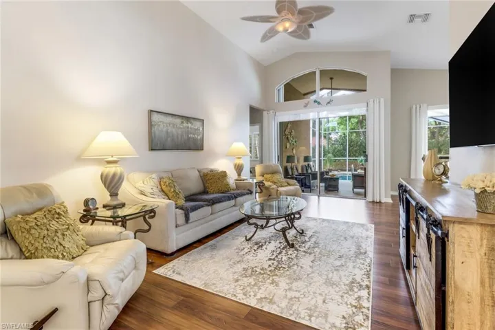 Living area with ceiling fan, high vaulted ceiling, and dark wood-style flooring