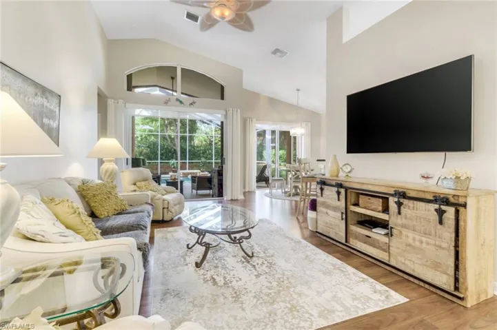 Living room with a ceiling fan, high vaulted ceiling, and wood finished floors