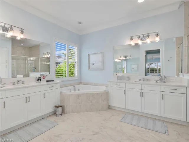 Full bath featuring a shower stall, two vanities, a garden tub, and quartz counters and tile floors