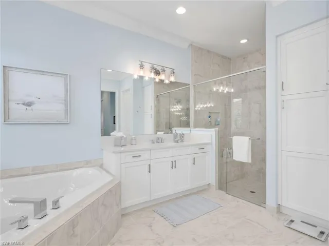 Full bath featuring vanity, quartz counters, a bath, a walk-in shower, tile floors, and recessed lighting