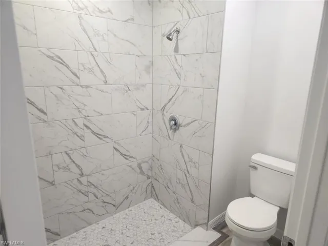 Bathroom featuring tiled shower and toilet