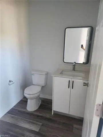 Bathroom featuring hardwood / wood-style flooring, vanity, and toilet