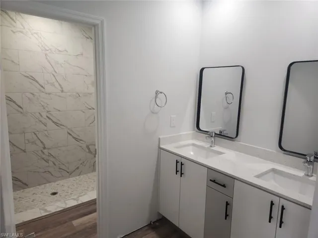 Bathroom featuring vanity, wood-type flooring, and tiled shower