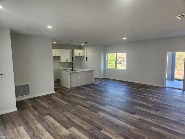 Unfurnished living room featuring dark hardwood / wood-style flooring, a healthy amount of sunlight, and sink