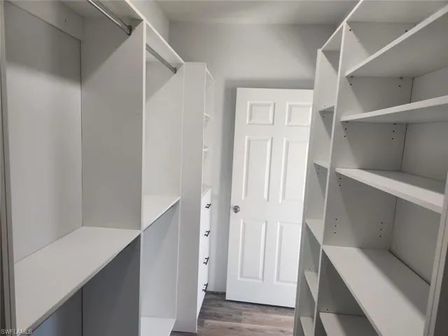 Spacious closet with dark wood-type flooring