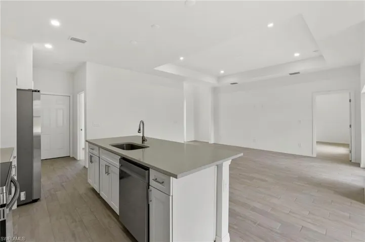 Kitchen with white cabinetry, sink, stainless steel appliances, and a raised ceiling