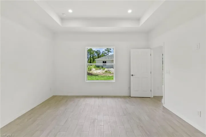 Empty room featuring light hardwood / wood-style floors and a tray ceiling