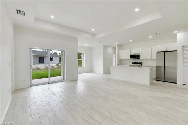 Unfurnished living room featuring a raised ceiling, light hardwood / wood-style floors, and sink