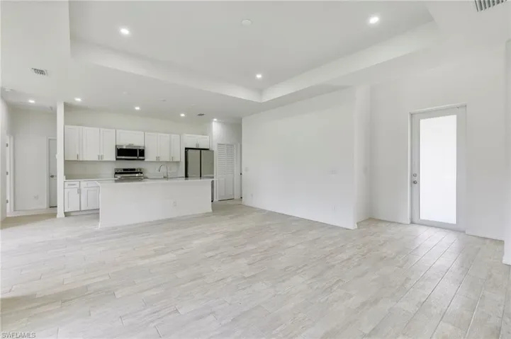 Unfurnished living room featuring light hardwood / wood-style floors, sink, and a raised ceiling