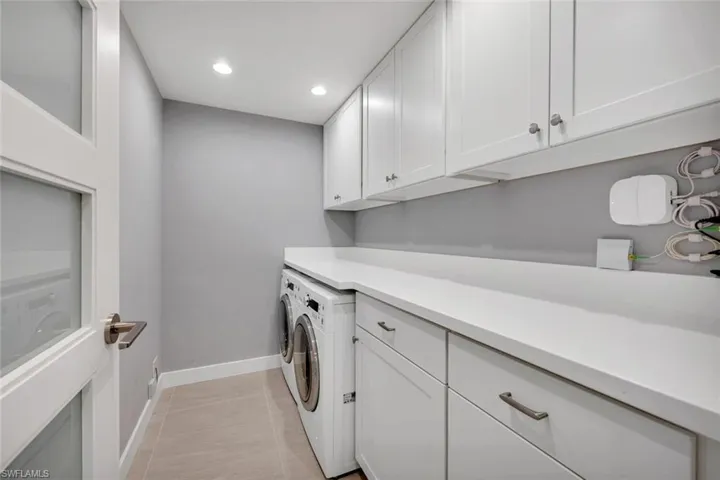 Washroom with cabinets, light tile patterned floors, and washer and dryer