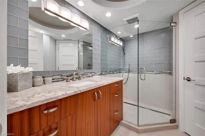 Bathroom featuring vanity, backsplash, and a shower with door