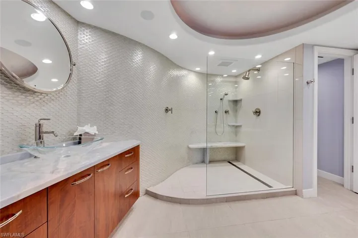 Bathroom featuring vanity, tiled shower, and tile patterned floors