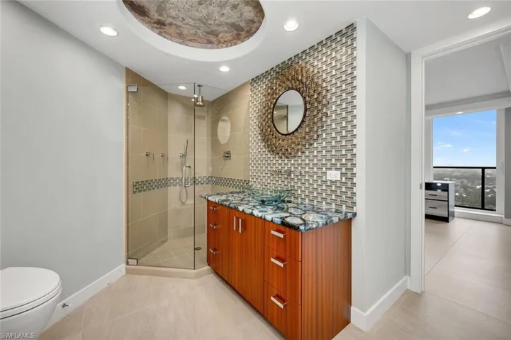 Bathroom featuring decorative backsplash, vanity, toilet, a shower with door, and tile patterned floors