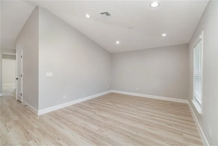 Additional living space featuring light hardwood / wood-style floors, a healthy amount of sunlight, and lofted ceiling