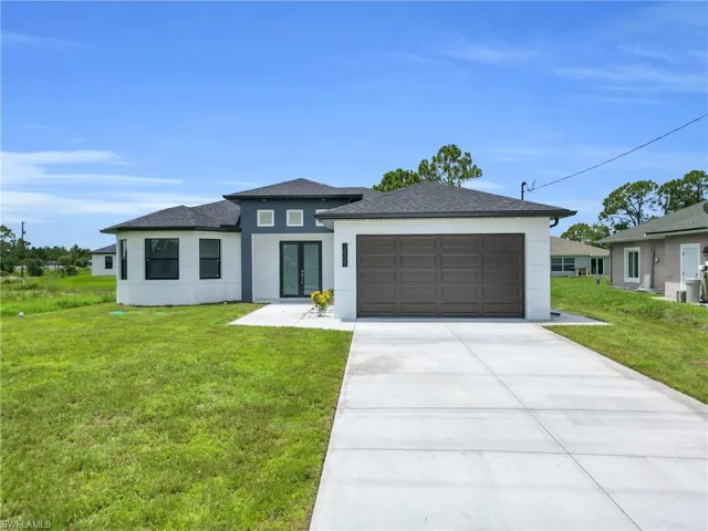 Prairie-style house with stucco siding, french doors, an attached garage, and a front lawn