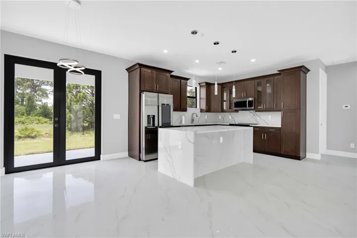 Kitchen featuring stainless steel appliances, dark brown cabinets, a kitchen island, glass insert cabinets, and recessed lighting