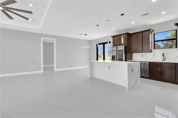 Kitchen with appliances with stainless steel finishes, light marble finish floors, recessed lighting, dark brown cabinetry, and hanging light fixtures