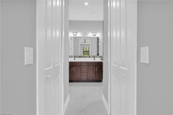Full bathroom featuring marble finish floors, double vanity, and recessed lighting