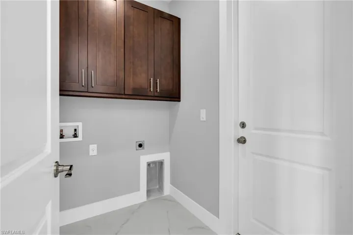 Washroom featuring cabinet space, electric dryer hookup, hookup for a washing machine, and light marble finish floors