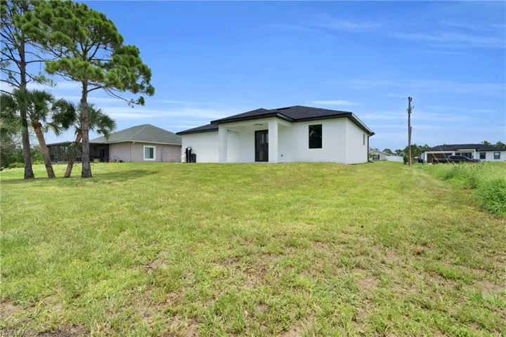 Rear view of house featuring a lawn and stucco siding