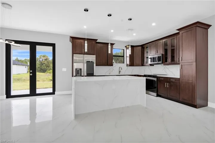 Kitchen with stainless steel appliances, a center island, glass insert cabinets, dark brown cabinetry, and pendant lighting