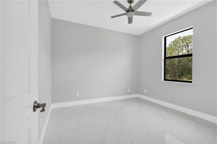 Unfurnished room featuring marble look tiles and a ceiling fan