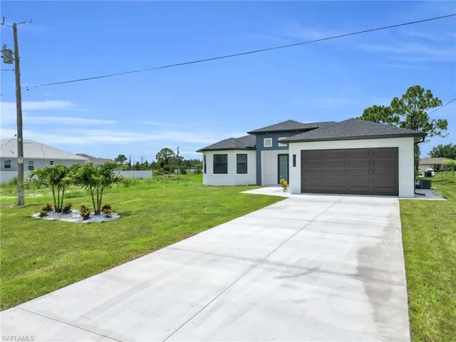 View of front of house with stucco siding, an attached garage, driveway, and a front yard