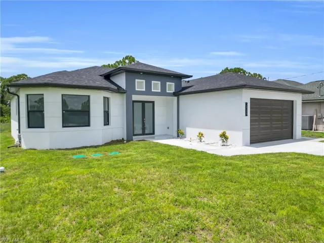 Prairie-style house featuring french doors, stucco siding, an attached garage, and driveway