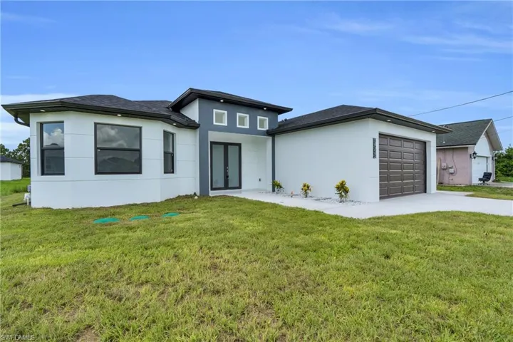 View of front of home featuring french doors, stucco siding, an attached garage, concrete driveway, and a front lawn