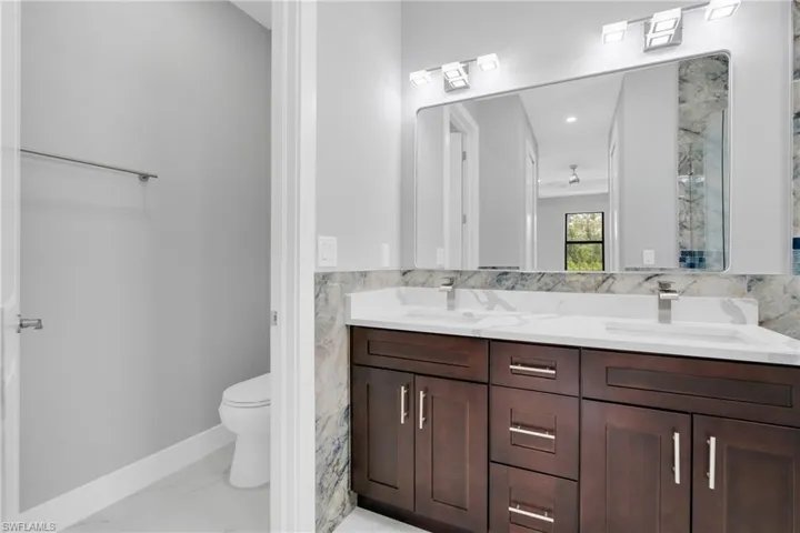Full bath featuring double vanity and marble finish floors