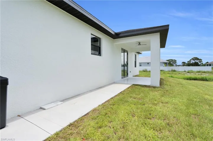 View of grassy yard with a patio area and a ceiling fan